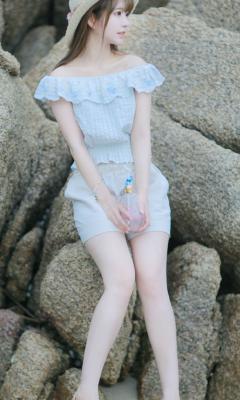 女孩穿着碎花裸肩上衣坐在海边礁石上手机壁纸
