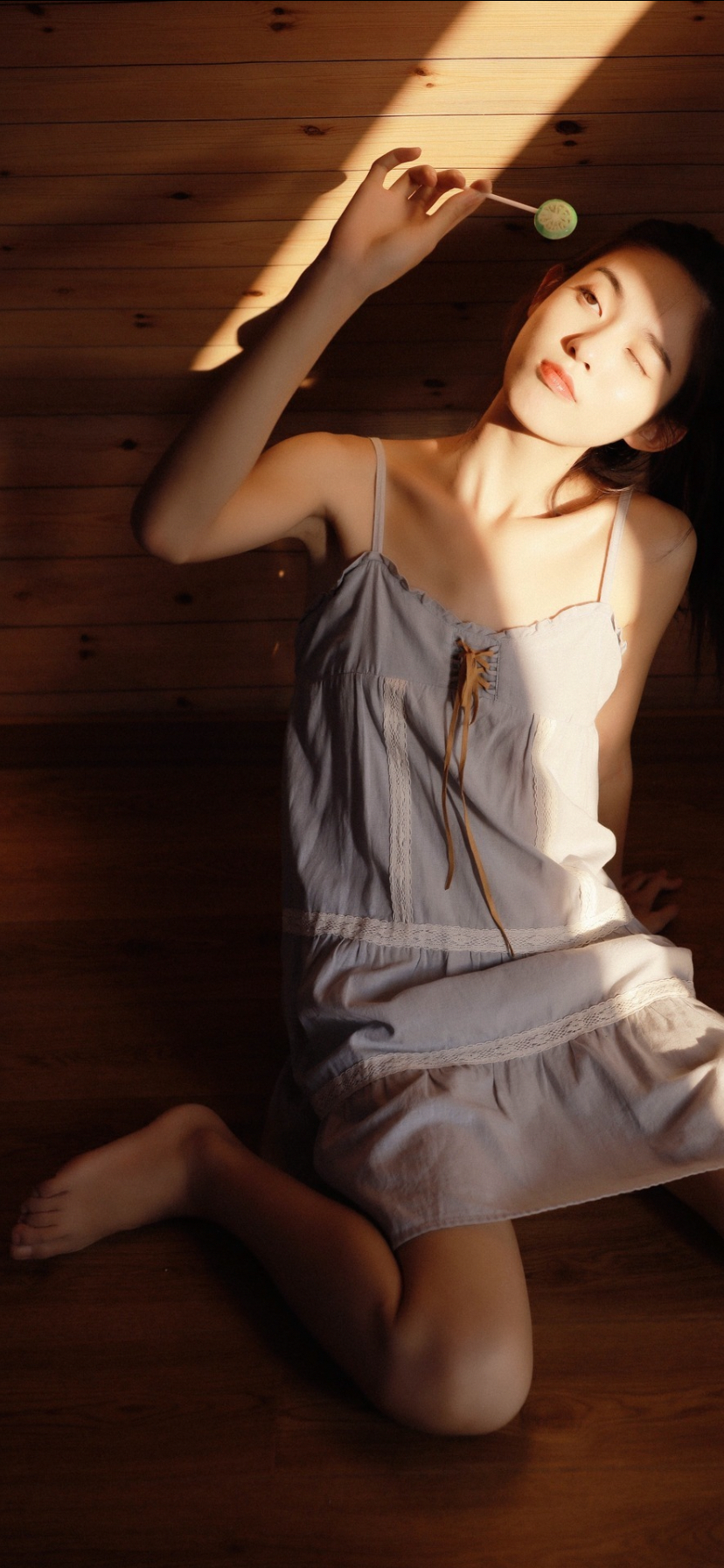 美女穿着吊带睡裙跪坐在地上吃棒棒糖手机壁纸