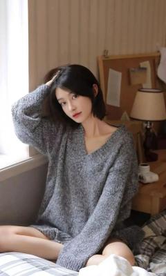 短发美女穿着灰色V领毛衣坐在床上手机壁纸