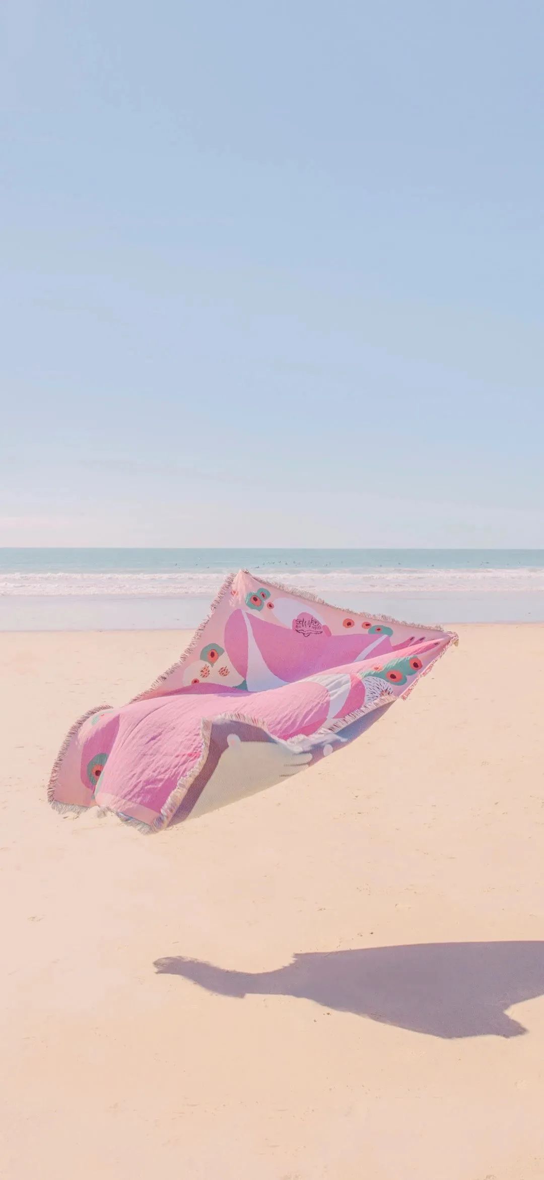 沙滩上飘起的粉色被子手机壁纸