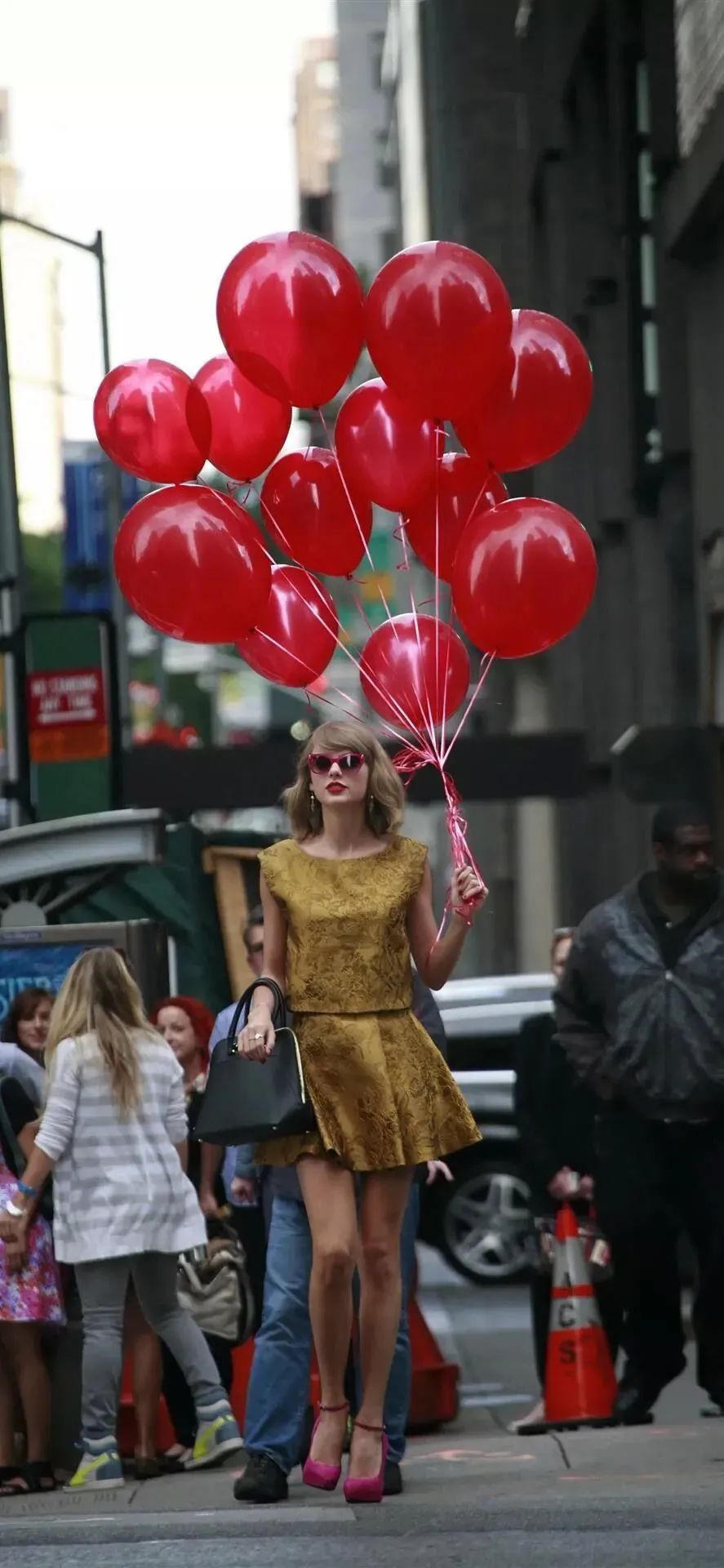 穿金色连衣裙拿红色气球的美女走在街头手机壁纸